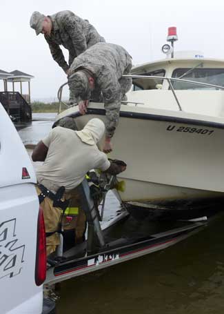 U.S. Air Force airmen align a fire and rescue boat with a hitch to tow the boat away from the Langley Marina at Langley Air Force Base, Virginia, Oct. 1, 2015. Heavy precipitation, high winds, storm surges, and flooding associated with Hurricane Joaquin caused personnel to take action. 