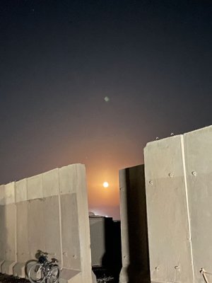 A blood moon shines over the blast walls that surround Cameron McMillan’s living area at Al Asad Air Base, Iraq. The entrance to a bunker, surrounded by Hesco barriers, can be seen through the break in the blast walls. Photo courtesy of the author.