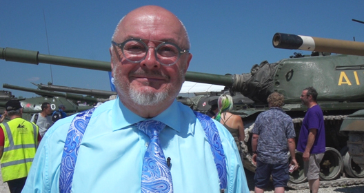 Bruce Compton standing near a row of military tanks