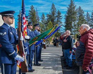 Lou Sherry, U.S. Air Force veteran, right, stands at attention as the Fairchild Air Force Base Honor Guard presents the colors at a Spokane Vet Center event in March in Spokane Valley, Washington. Photo courtesy of Dan Pelle/The Spokesman-Review.
