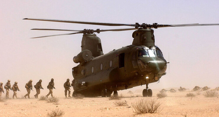 British troops walking toward a Boeing CH-47 Chinook in the middle of the desert
